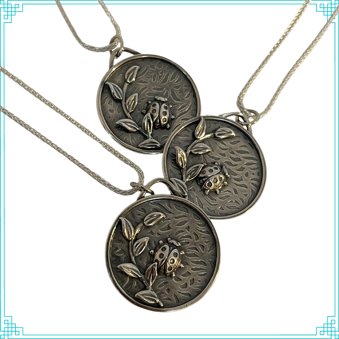 Sleeping Fox handmade silver jewelry created this round pendant with a lady bug and leafy branch elements. The background is a bed of leaves. This pendant hangs from an 18" wheat chain.