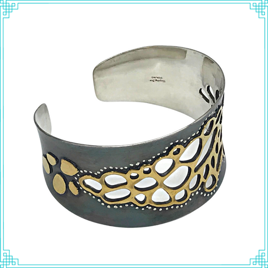 Sleeping Fox quality handmade silver jewelry presents Less is More Cuff Bracelet. This bracelet has a wonderful comfort fit due to it's anticlastic shape (curve going in two different directions). The base material is silver and the top elements are brass.  The whole piece has been given a patina of black and the patina has been polished off the brass.  The dot design is done with a ball bur and gives a lacy effect.