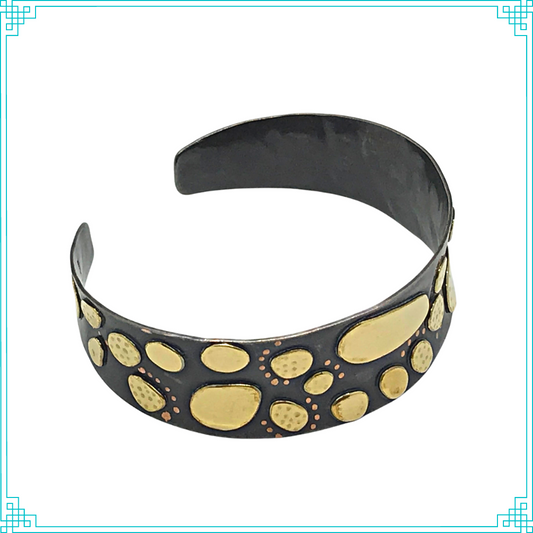 Sleeping Fox quality handmade jewelry presents Nuggets Cuff Bracelet. This bracelet has a wonderful comfort fit due to it's anticlastic shape. Anticlastic means the material has a curve going in two different directions. The base material is copper and the top elements are brass. The whole piece has been given a patina of black and the patina has been polished off the brass. The dot design is done with a ball bur.