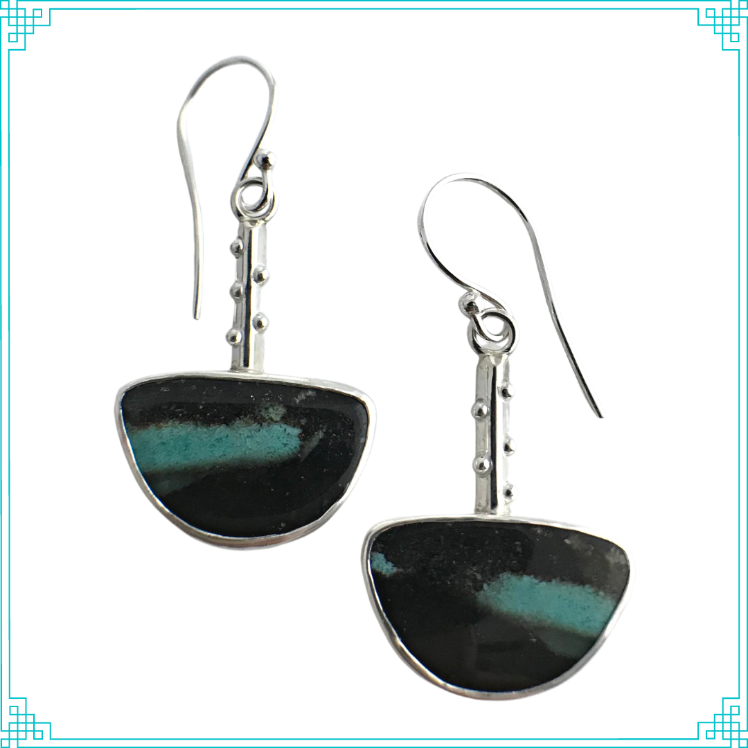 Sleeping Fox quality handmade jewelry presents sterling silver Petrified Wood Opal Drops. Found in Indonesia, these agatized, opalized, petrified wood stones are unique in many ways. Like a painting, nature swiped a contrasting abstract sea-blue streak through a black matrix. The fine silver textured backing and sterling silver triangle wires with soldered silver balls complete this design. These earrings hang from hand made sterling silver ear wires.
