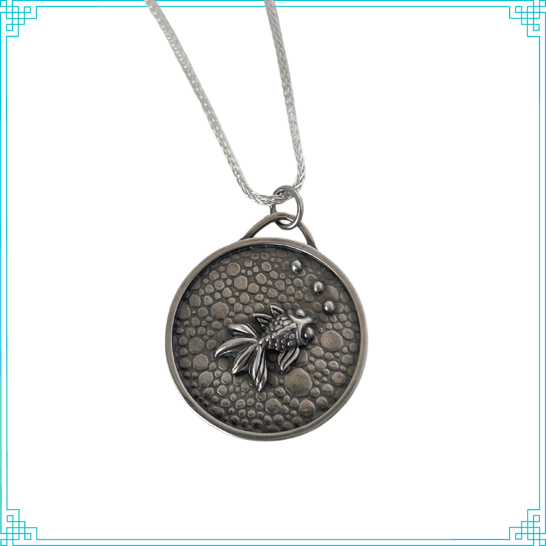 Sleeping Fox handmade silver jewelry pendant features a fish with bubbles swimming in a pebbled cement pond. 