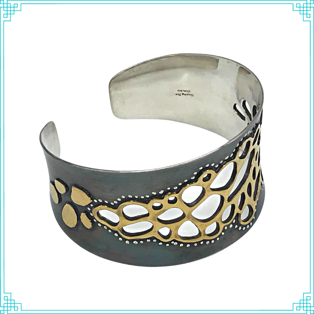 Sleeping Fox quality handmade silver jewelry presents Less is More Cuff Bracelet. This bracelet has a wonderful comfort fit due to it's anticlastic shape (curve going in two different directions). The base material is silver and the top elements are brass.  The whole piece has been given a patina of black and the patina has been polished off the brass.  The dot design is done with a ball bur and gives a lacy effect. 