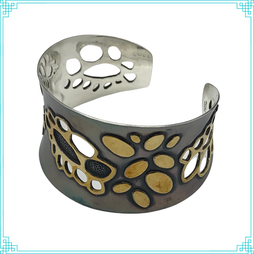 Sleeping Fox quality handmade silver jewelry presents Golden Doily Cuff Bracelet. This bracelet has a wonderful comfort fit due to it's anticlastic shape. Anticlastic means the material has a curve going in two different directions. The base material is silver and the top elements are brass. The outer face of the piece has been given a patina of black and the patina has been polished off the brass. 