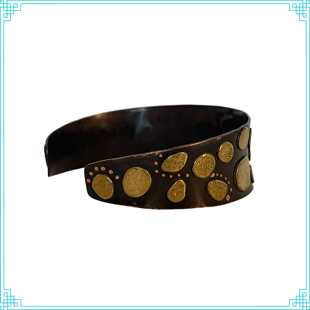 Sleeping Fox quality handmade jewelry presents Nuggets Cuff Bracelet. This bracelet has a wonderful comfort fit due to it's anticlastic shape. Anticlastic means the material has a curve going in two different directions. The base material is copper and the top elements are brass. The whole piece has been given a patina of black and the patina has been polished off the brass. The dot design is done with a ball bur.