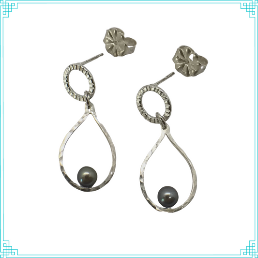 Sleeping Fox handmade sterling silver post earrings feature hammer-textured tear drops with black pearls sitting on soldered posts.